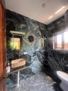 a black marble bathroom with a sink and a mirror at The Walnut House in Pahalgām