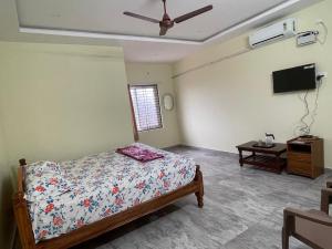 a bedroom with a bed and a tv on the wall at Amaravathi Residency in Nārāyanavanam