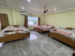 a room with three beds and a window at Amaravathi Residency in Nārāyanavanam