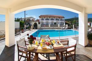 a villa with a swimming pool and a table with food at Diamanto Complex in Karavomylos