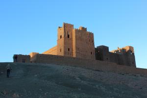 Tamnougalt的住宿－Kasbah Itrane，一个人在城堡前爬上山