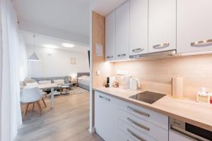 a kitchen with white cabinets and a living room at Rezidence Sadová Zlín in Zlín