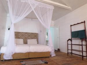 a bedroom with a canopy bed with white curtains at Why Not Guest house in Hikkaduwa