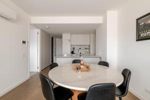 a white dining room with a table and chairs at Winx Trackside Moonee Ponds in Moonee Ponds