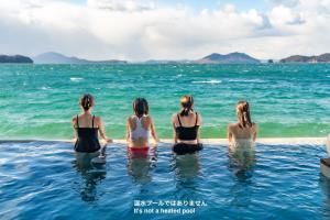 three women sitting in the water in the ocean at Sunset SPA Resort AJI by SETO CLAS in Takamatsu