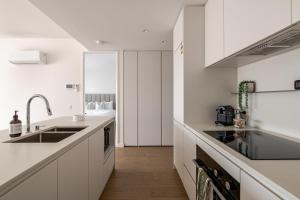 a white kitchen with white cabinets and a sink at Winx Trackside Moonee Ponds in Moonee Ponds