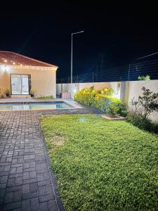 a backyard of a house with a swimming pool at night at Elle Residence in Gaborone