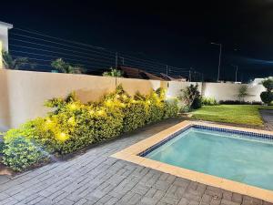 a swimming pool in front of a fence with flowers at Elle Residence in Gaborone