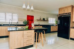a large kitchen with wooden cabinets and a black refrigerator at Elle Residence in Gaborone