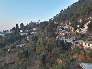 a village on a hill with houses on it at Hotel Avlokan - Near Kainchi Dham Mandir in Bhowāli