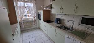 a kitchen with white cabinets and a sink and a window at Boxspring Apartment Rottweil mit Stellplatz in Rottweil