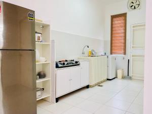 a kitchen with white cabinets and a refrigerator at Izans Homestay Sendayan in Seremban