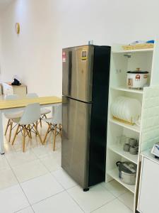 a refrigerator in a kitchen with a table and chairs at Izans Homestay Sendayan in Seremban +4 photos