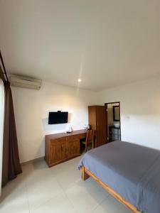 a bedroom with a bed and a desk and a television at Wisna House in Sanur
