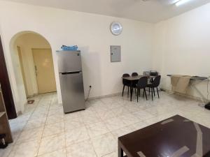 a kitchen and dining room with a refrigerator and a table at Catchy & Traveler-Friendly Room in Dibba