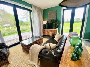 a living room with a leather couch and a table at Stablehouse Garden Shed in Masterton