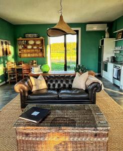 a living room with a leather couch and a window at Stablehouse Garden Shed in Masterton