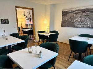 ein Esszimmer mit weißen Tischen und grünen Stühlen in der Unterkunft harmony holiday, Pension in Kerschenbach
