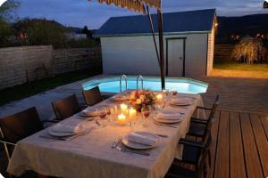 a long table with candles and plates and a pool at Villa 1950 piscine et spa- Gérardmer - terrain entièrement clos pour animaux in Anould