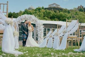 a bride and groom standing in front of a wedding arch at The Glasshouse, Autograph Collection in Edinburgh