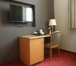 a hotel room with a desk and a television on the wall at Albion Hotel in Ieper