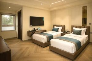 two beds in a hotel room with a flat screen tv at Qotel Signature Coleman Janakpuri Near District Centre & Pacific Mall in New Delhi