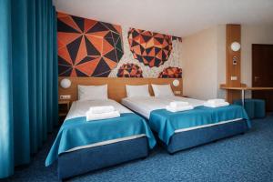 two beds in a hotel room with a mural at WESTGATE Hotel - FREE PARKING in Veliko Tŭrnovo