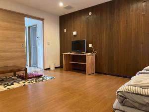 a living room with a tv and a wooden wall at Takamori Guest House in Takamori