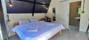 a bedroom with a large bed with blue sheets and pillows at บ้านไม้หอมชาเล่ต์ in Suan Phung