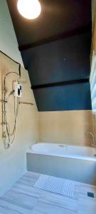 a bathroom with a shower and a bath tub at บ้านไม้หอมชาเล่ต์ in Suan Phung