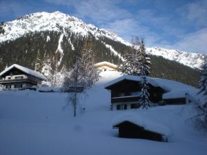 ein Haus im Schnee vor einem Berg in der Unterkunft Appartements Hexahüsle in Wald am Arlberg