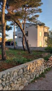 a stone wall next to two trees and a building at Apartman TIA in Vir +18 photos