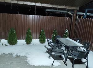 a table and chairs in the snow with christmas trees at Дім весняний in Sheremetka