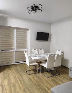 a dining room with a table and white chairs at Дім весняний in Sheremetka