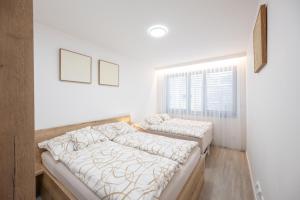 two beds in a room with white walls and a window at Rezidence Sadová Zlín in Zlín