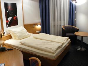 um quarto de hotel com uma cama e uma cadeira em Mirage City Hotel Stuttgart Zentrum em Stuttgart