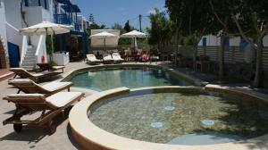 a swimming pool with chairs and an umbrella at Dimitra Hotel in Agios Prokopios