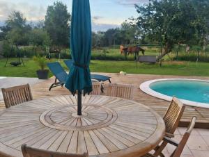 an umbrella sitting on a wooden table next to a pool at Chambre Colomby Kaabi in Colomby