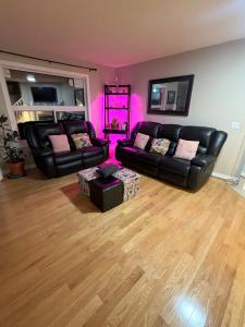 a living room with black leather furniture and pink lighting at Jeli haus in Calgary