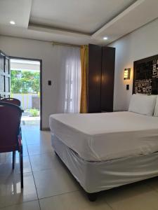 a bedroom with a large white bed and a window at Silk Mbare Guest House in Manzini