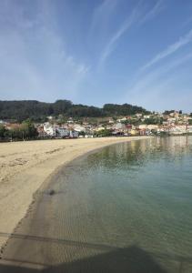 a sandy beach with a town in the background at A beira do Mar in Bueu