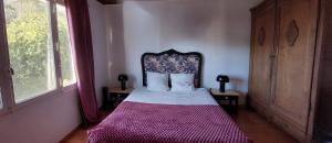 a bedroom with a bed with a headboard and two windows at CAP AZUR ILE du LEVANT in Île du Levant
