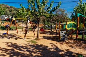 a park with a playground with a tree at Camping El Pasqualet in Caldes de Montbui