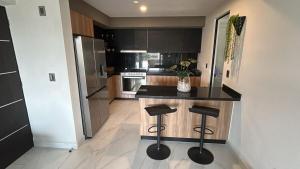 a kitchen with a counter and two stools in it at Santa Fe Dorado Atardecer in Atlacholoaya