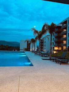 a swimming pool with palm trees and a building at Santa Fe Dorado Atardecer in Atlacholoaya