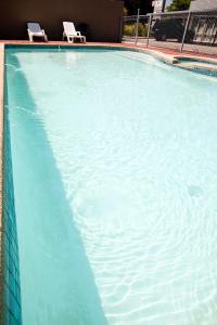 a large blue swimming pool with two chairs in it at Mansfield Motel in Mansfield