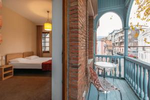 a room with a balcony with a bed and a table at Tekla Palace By Urban Hotels in Tbilisi City