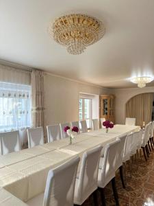 a long table with white chairs and a chandelier at Усадьба in Kostanay +8 photos
