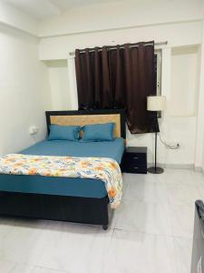 a bedroom with a bed with blue sheets and a window at Staywise in Indore