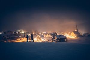 two people standing on top of a hill looking at a city at JONI Apartments Berwang in Berwang +3 photos